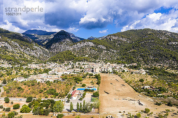 Luftaufnahme eines Dorfes in der Nähe von Bergen bei bewölktem Himmel an einem sonnigen Tag  Caimari  Mallorca  Spanien