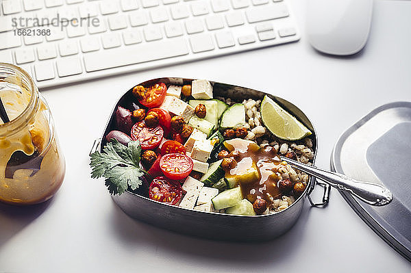 Lunchbox mit frischem veganem Salat auf dem Schreibtisch vor der Computertastatur