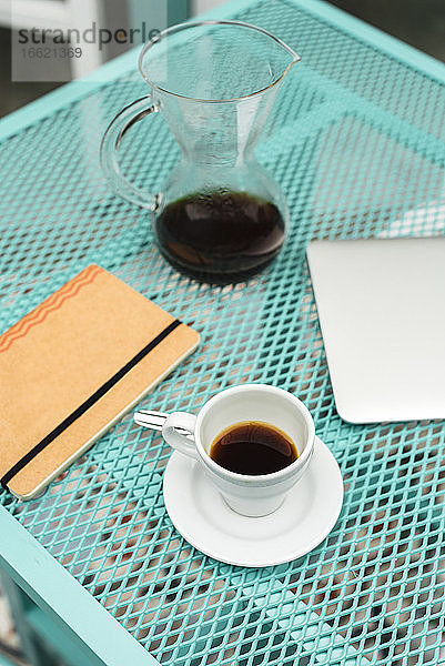 Notizblock  Laptop  Kaffeetasse und Kanne auf dem Tisch eines Cafés