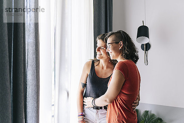 Freunde schauen durch das Fenster  während sie zu Hause stehen