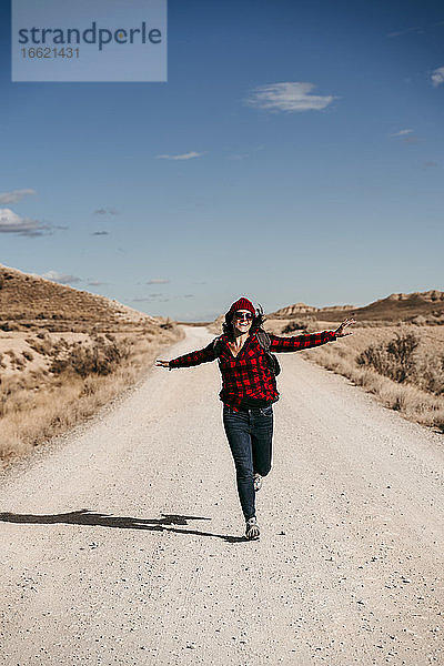 Spanien  Navarra  Weibliche Touristin  die auf einem leeren Feldweg in Bardenas Reales in Richtung Kamera läuft