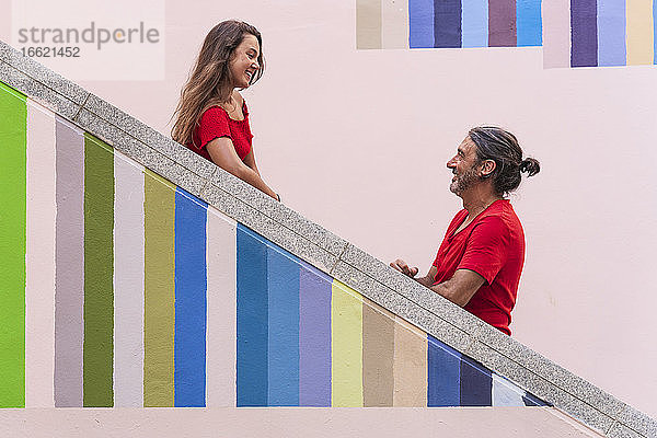 Vater und Tochter stehen auf einer bunten Treppe an einem sonnigen Tag