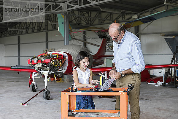 Enkelin und Großvater wählen Werkzeuge zur Reparatur von Flugzeugen aus