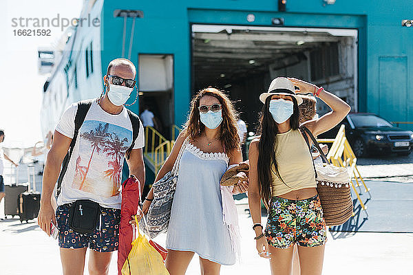 Freunde mit Masken stehen vor einem Kreuzfahrtschiff im Hafen