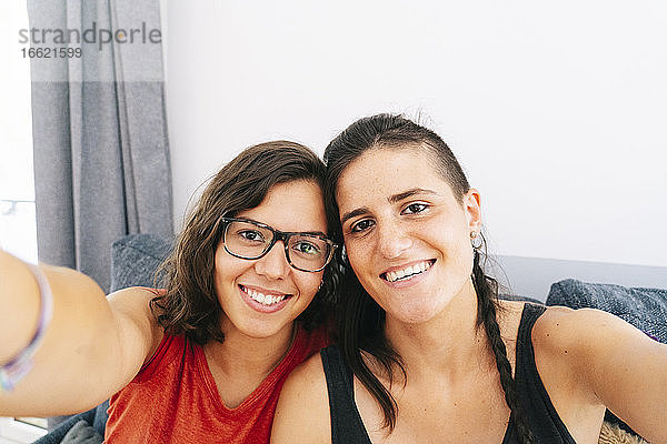 Weibliche Freunde nehmen Selfie beim Sitzen zu Hause