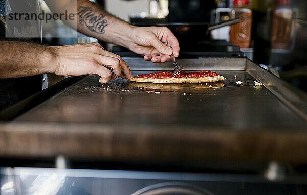 Männlicher Koch bereitet Tomatensandwich in einem Café zu