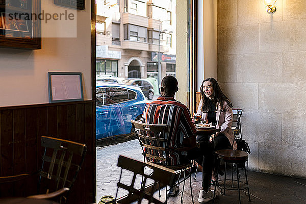 Glückliche junge Frau mit Freund im Café