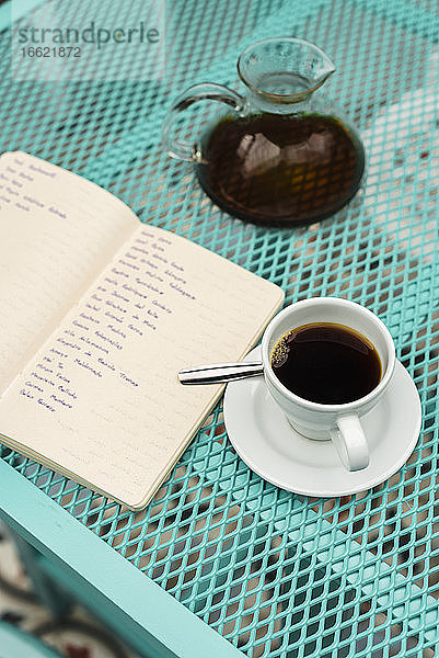 Hochformatige Ansicht eines Buches  einer Kaffeetasse und einer Kanne auf dem Tisch