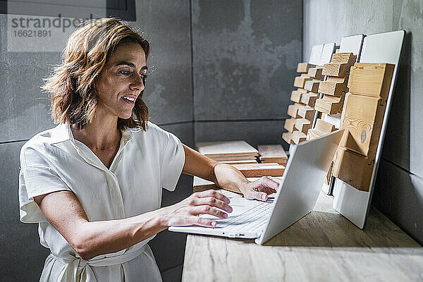 Geschäftsfrau arbeitet am Laptop mit Holzfliesen auf dem Schreibtisch im Büro