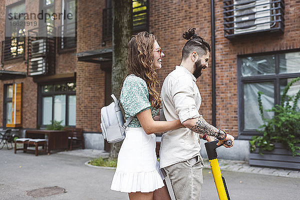 Glückliches Paar fährt elektrischen Roller auf der Straße in der Stadt