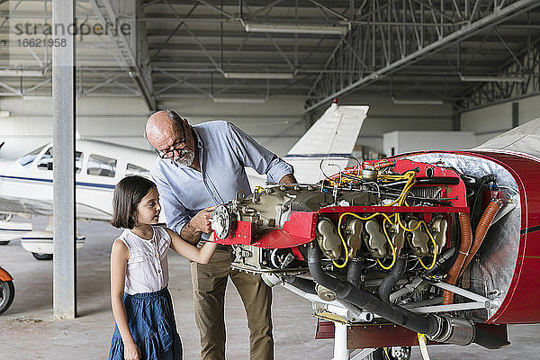 Großvater zeigt seiner Enkelin  wie man ein Werkzeug für ein Flugzeug repariert