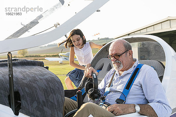 Junges Mädchen im Cockpit eines Flugzeugs mit Großvater auf dem Flugplatz