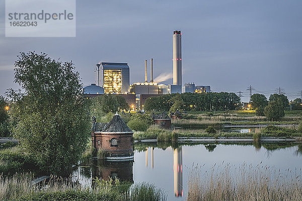 Deutschland  Hamburg  Pumpenhaus des ehemaligen Wasserwerks auf der Elbinsel Kaltehofe mit Tiefstack-Kraftwerk im Hintergrund in der Abenddämmerung