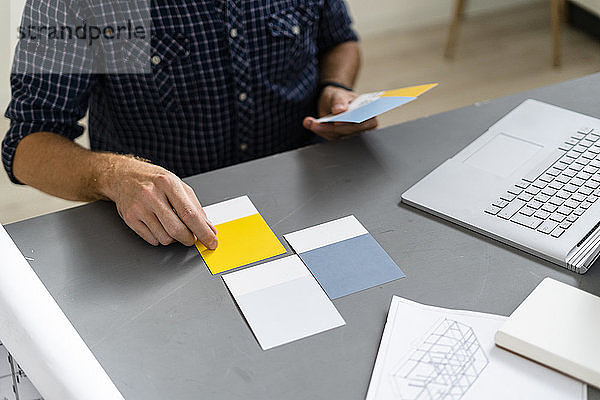 Architekt wählt Farbmuster aus  während er am Schreibtisch im Büro sitzt