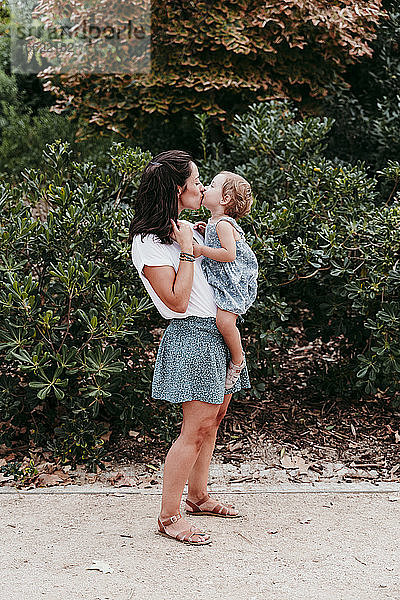 Mutter und Tochter küssen sich in einem öffentlichen Park
