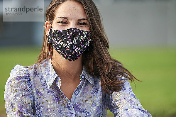 Frau mit Gesichtsschutzmaske in der Stadt sitzend
