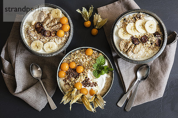 Drei Schalen Porridge mit Haferflocken  Leinsamen  Winterkirschen und Bananen