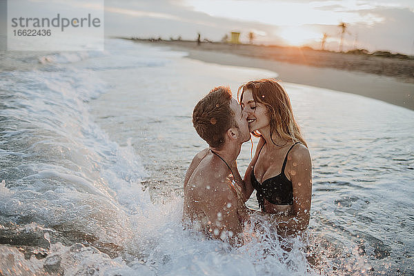 Paar beim Sitzen im Wasser am Strand romantisch