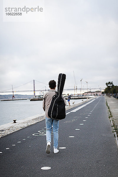 Junger Mann mit Gitarre auf der Promenade