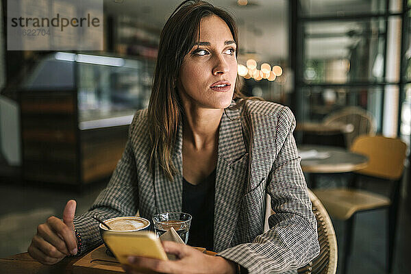 Junge Frau schaut weg  während sie in einem Café sitzt