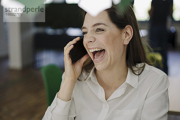 Frau lachend beim Telefonieren im Büro