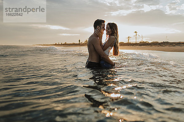 Romantisches Paar im Wasser stehend am Strand