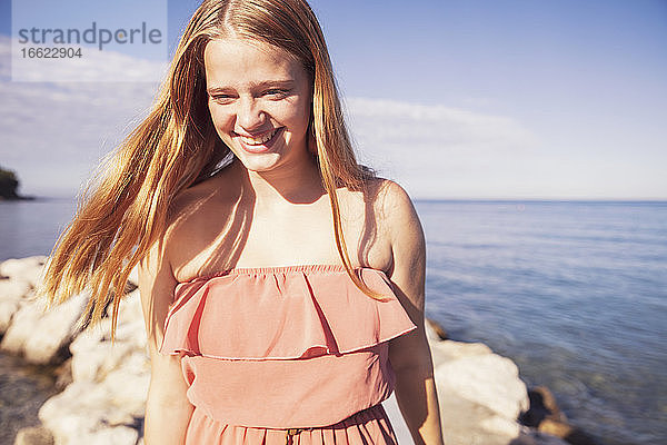 Teenager-Mädchen stehend gegen das Meer an einem sonnigen Tag