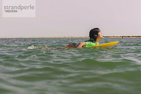 Lächelndes Mädchen Bodyboarding auf Meer gegen klaren Himmel