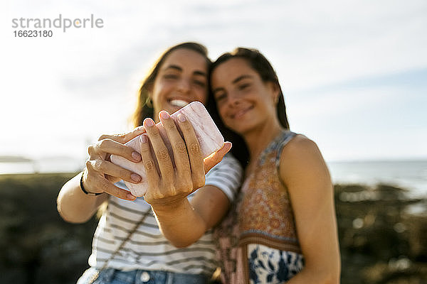 Glückliche junge Schwestern nehmen Selfie durch Smartphone am Strand während des Wochenendes