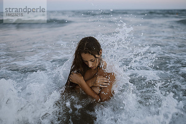 Junge Frau beim Baden im Meer bei Sonnenuntergang