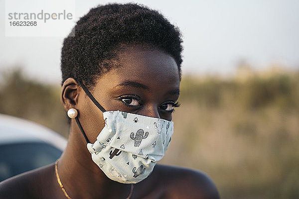 Junge Frau mit Gesichtsschutzmaske auf einem Feld
