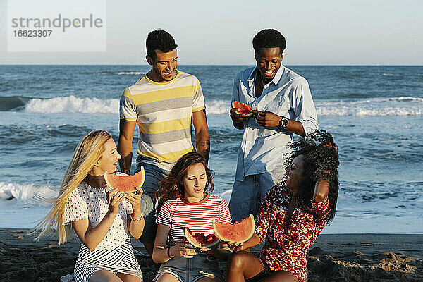 Freunde genießen beim Essen einer Wassermelone an einem sonnigen Tag