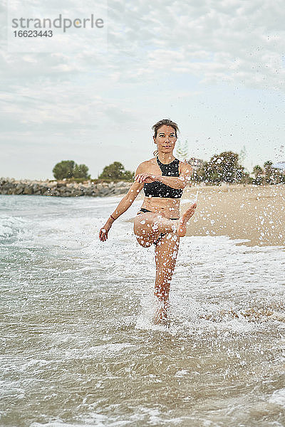 Frau  die am Ufer stehend Wasser spritzt