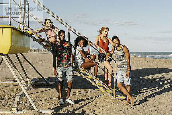 Junge Freunde lehnen auf den Stufen der Rettungsschwimmerhütte am Strand