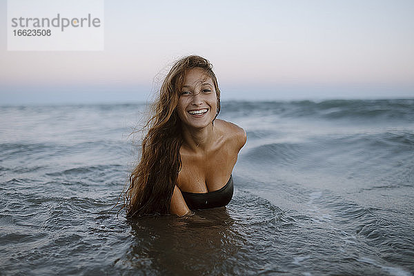 Lächelnde junge Frau genießt das Meer am Strand