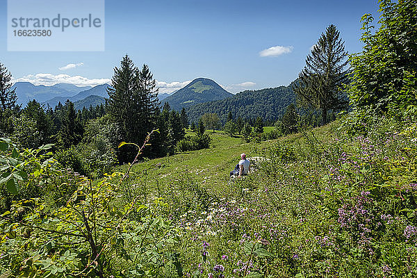 Ältere Frau entspannt sich im Sommer auf einer Bergwiese