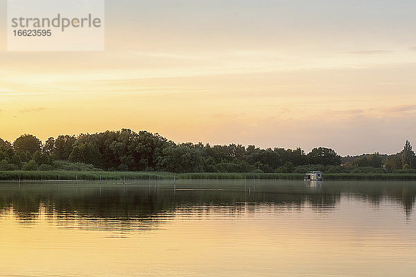 Fernblick auf ein Hausboot im See bei Sonnenuntergang