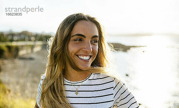 Glückliche junge Frau schaut weg  während sie ein Wochenende am Strand bei Sonnenschein verbringt