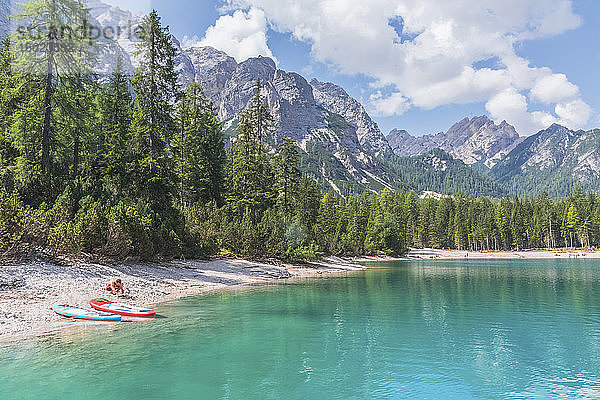 Mann mit Paddelbrett am Ufer des Pragser Wildsees an einem sonnigen Tag  Dolomiten  Südtirol  Italien