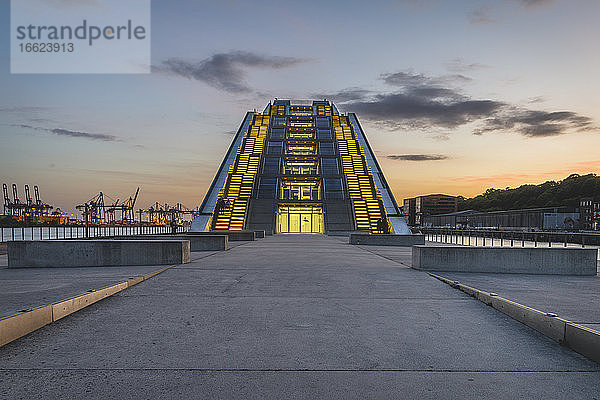 Deutschland  Hamburg  Beleuchtetes modernes Bürogebäude in der Nähe des Docks bei Sonnenuntergang