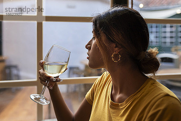 Schöne lateinische Frau trinkt Weißwein an der Bar