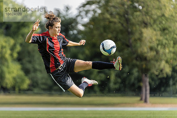 Junge Frau spielt Fußball auf einem Feld