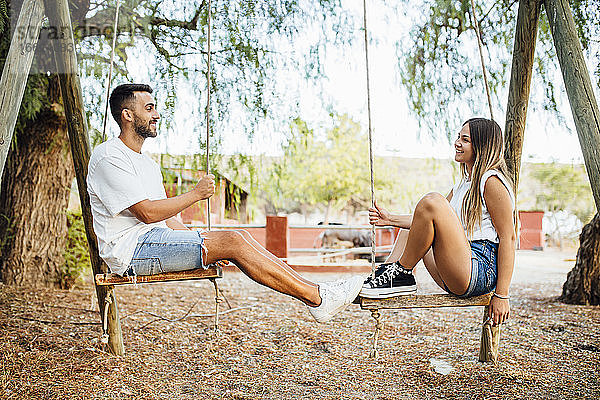 Junges Paar verbringt Zeit auf einer Schaukel in einem öffentlichen Park