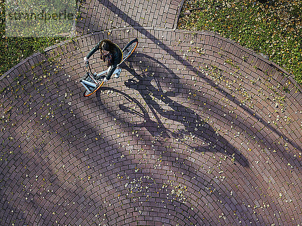 Luftaufnahme einer jungen Frau beim Fahrradfahren im Herbstpark
