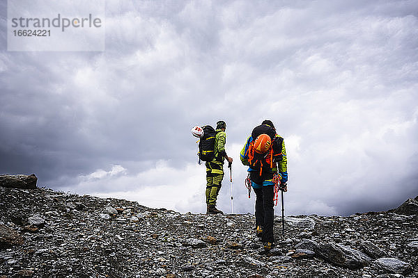 Männliche Freunde wandern auf einem Berg gegen den bewölkten Himmel im Stilfserjoch-Nationalpark  Italien
