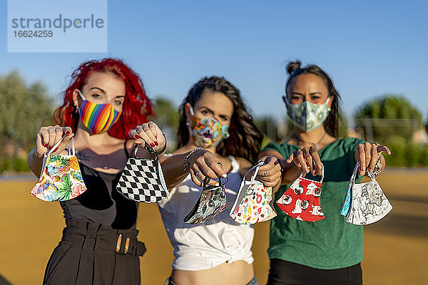 Freunde halten eine mehrfarbige Gesichtsmaske  während sie im Freien stehen