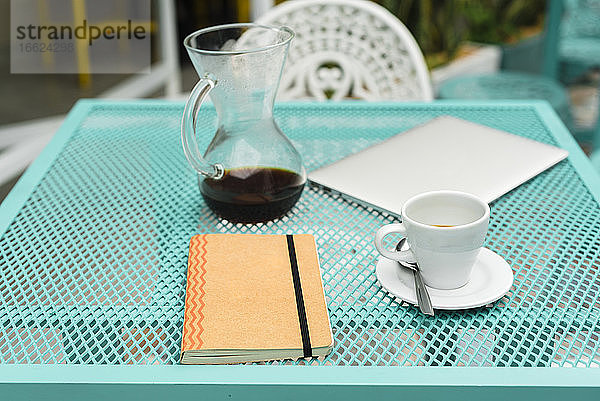 Tisch mit Notizblock  Laptop  Kaffeetasse und Kanne im Café