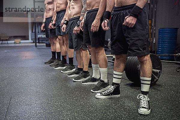 Sportler ohne Hemd mit Sportschuh und Shorts im Fitnessstudio