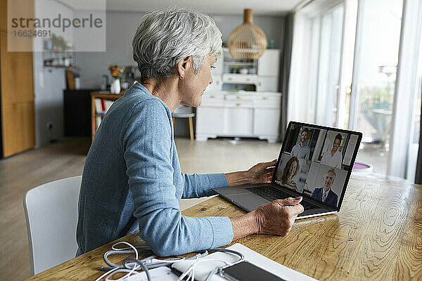 Aktive ältere Frau  die an einer Videokonferenz teilnimmt  während sie zu Hause sitzt