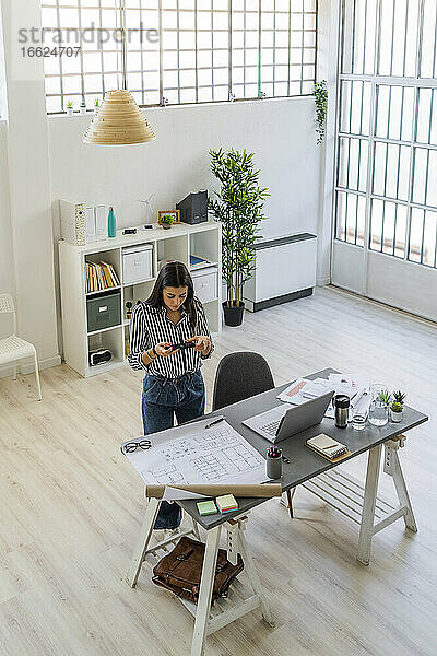 Weibliche Design-Profis fotografieren Grundriss am Schreibtisch in kreativen Arbeitsplatz